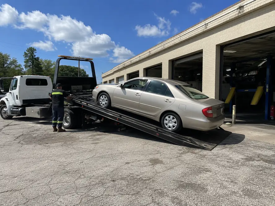 Tow truck delivering a car to an auto repair shop in Humble