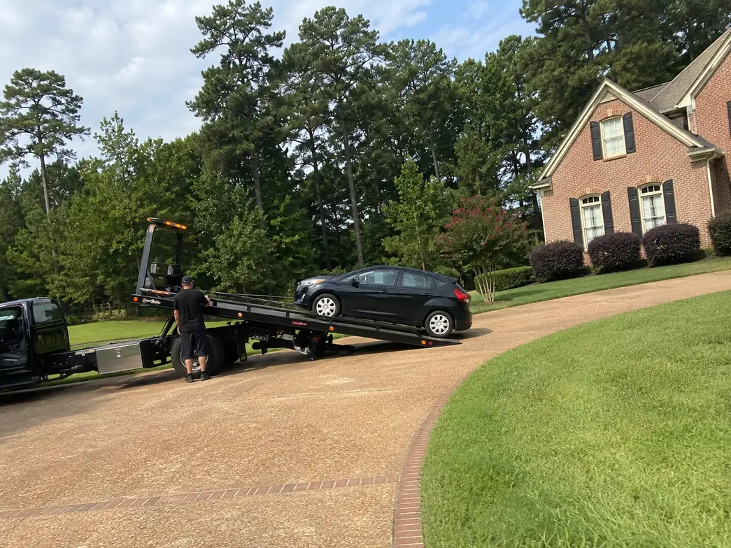 Flatbed tow truck loading a car in a Humble TX driveway